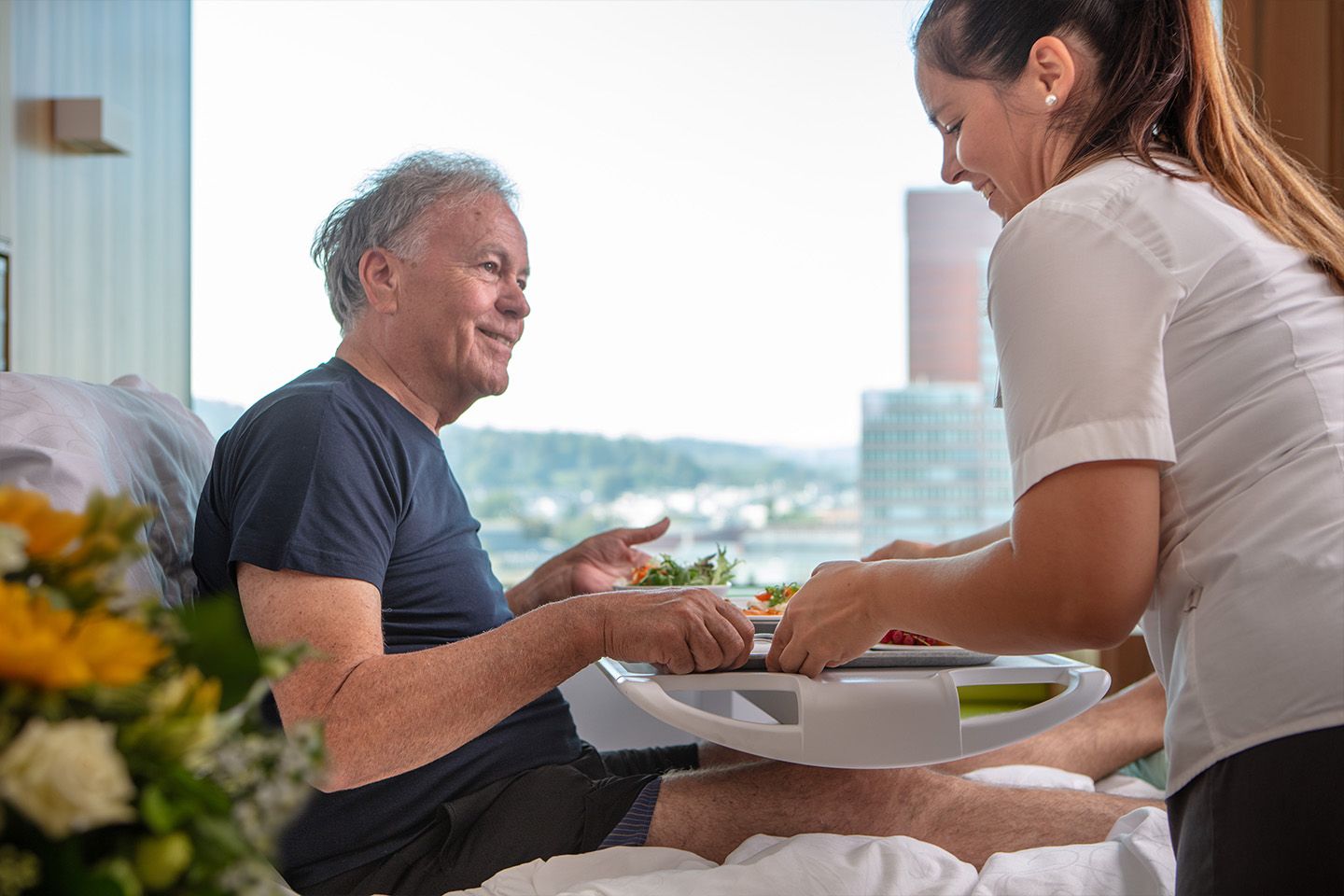 Einem Patienten wird das Essen im Spitalbett serviert. Dank seiner Zusatzversicherung profitiert er von KSW Premium Mehrleistungen.